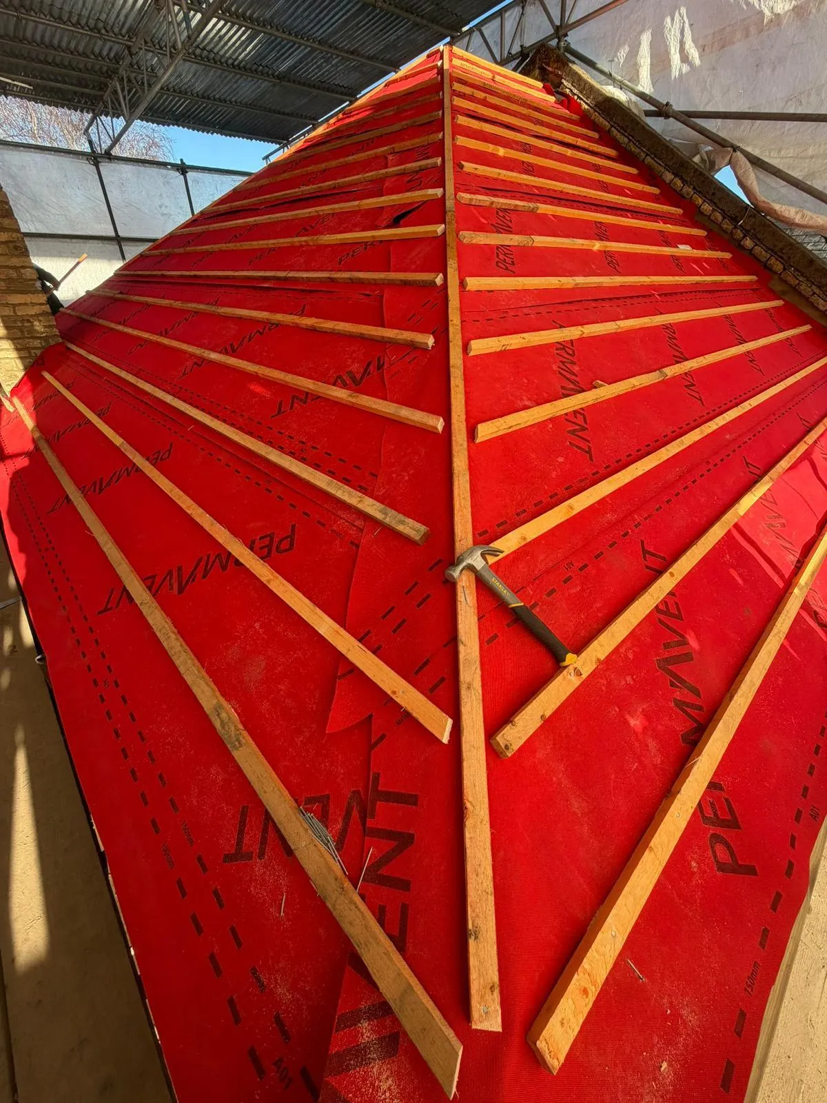 Battens over red breathable membrane on a hip roof during a re-roof