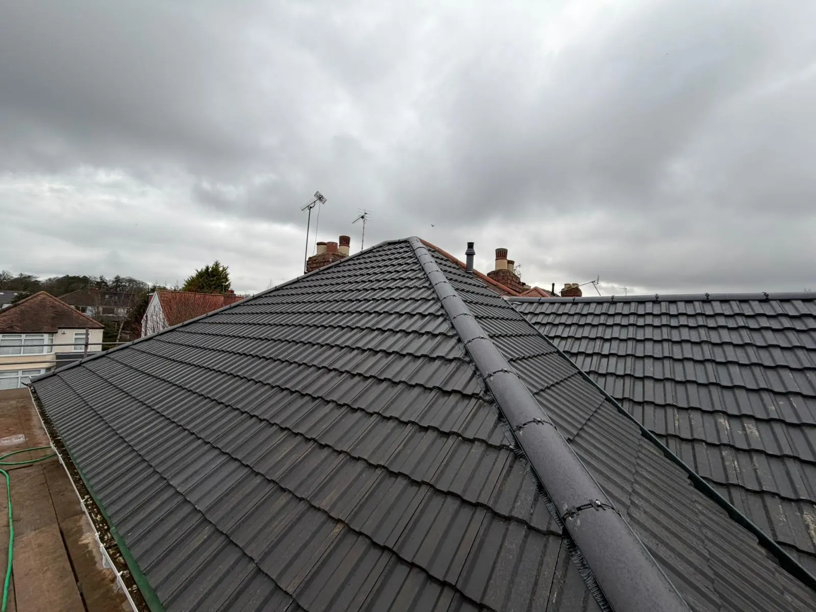 New dark grey tiled hip roof with a ridge