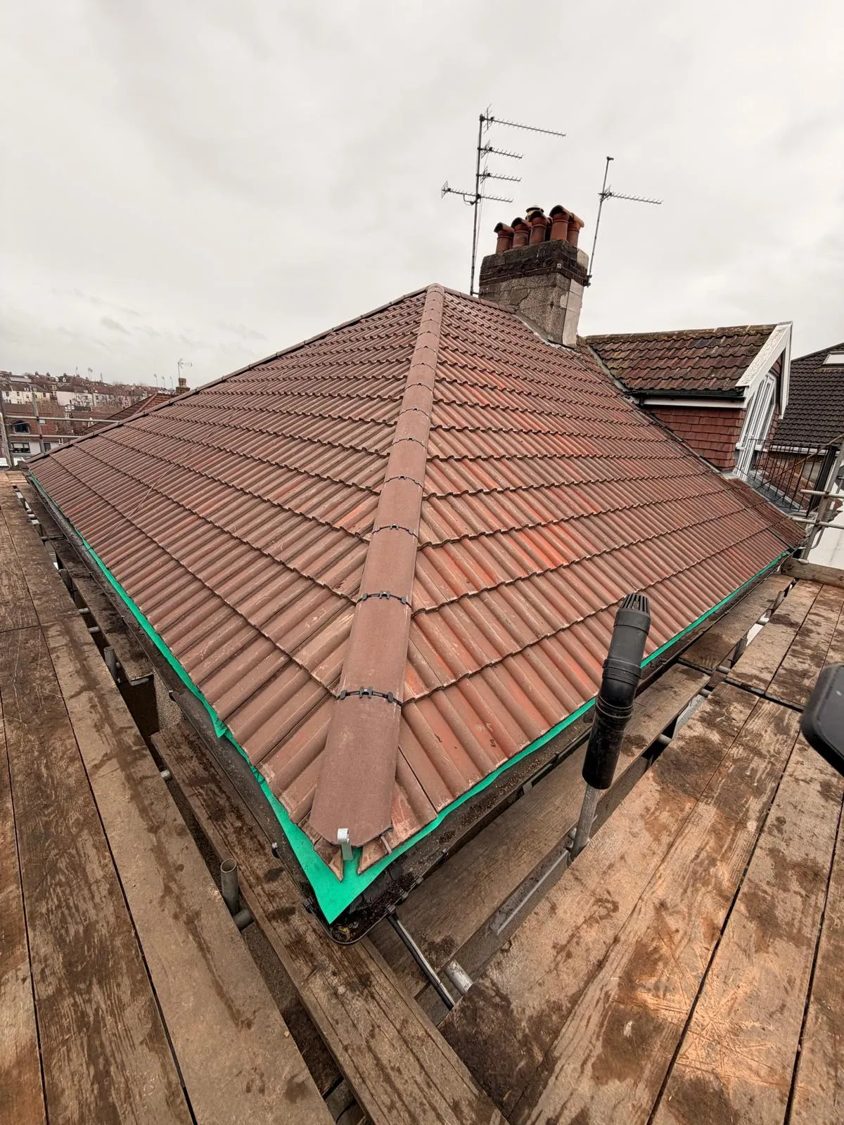 New red tiled hip roof with a brick chimney