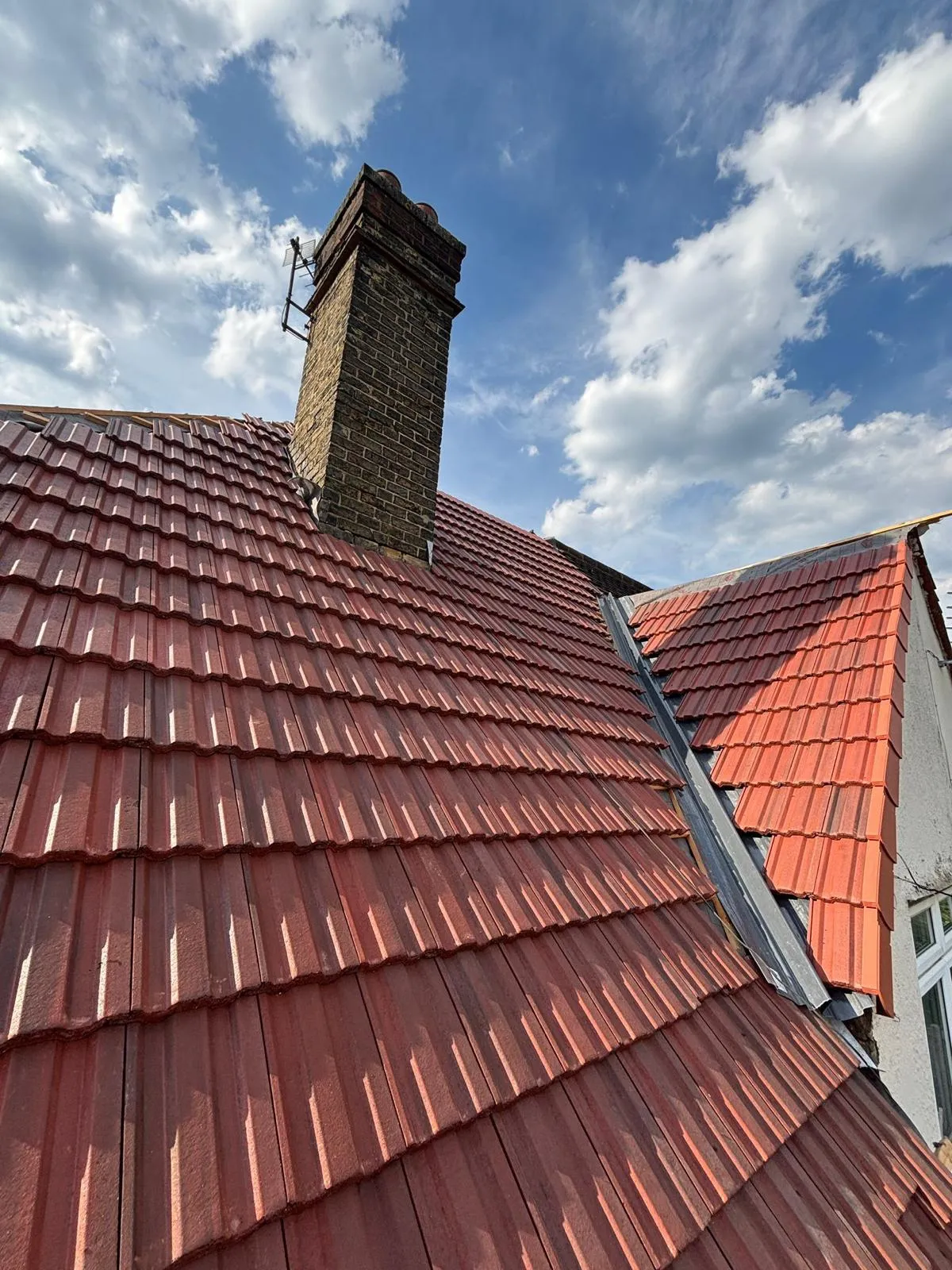 New red tiled roof with a chimney and valley