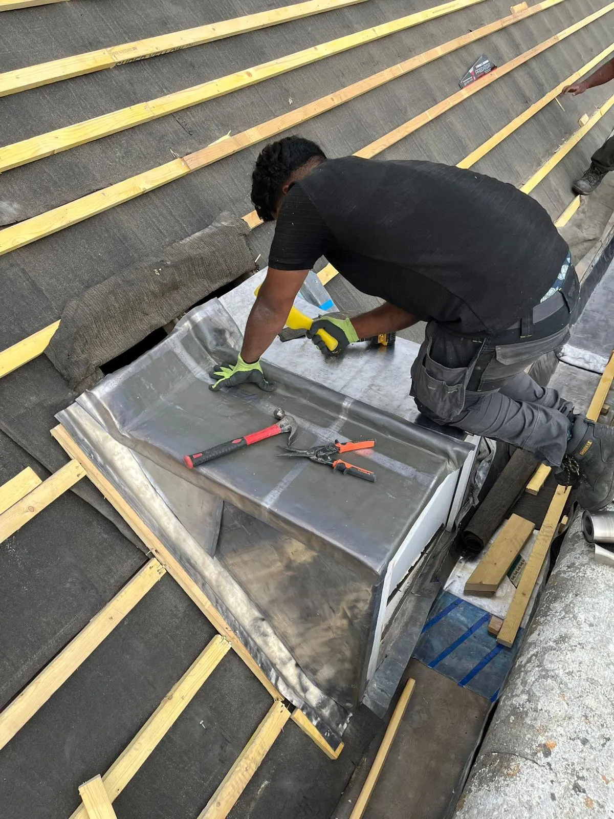 Roofer dressing new lead flashing around a chimney base