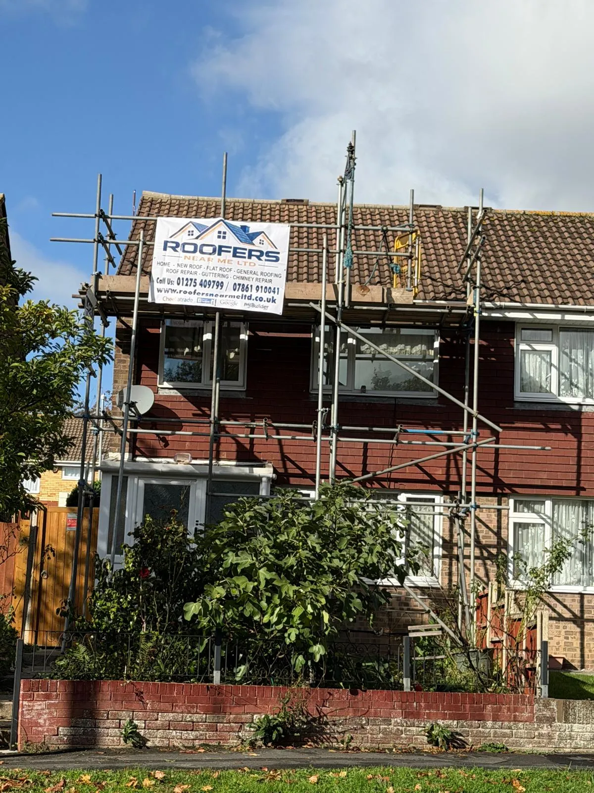 Roofers Near Me banner on the scaffold of a semi-detached house during a roofing job